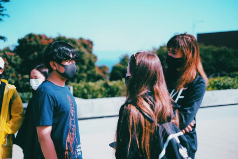 Three people standing outside talking with masks on during coronavirus time