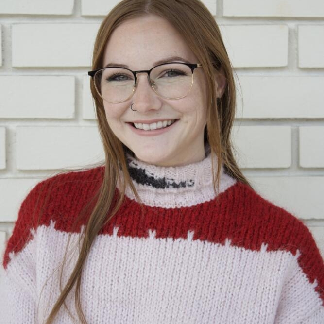 Smiling picture of Madalyn Wright with long red hair and glasses