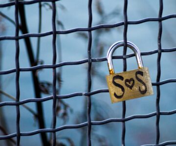 lock on fence with 'sos' reference that also appears as 's loves s' because a heart-shape stands in for 'o'