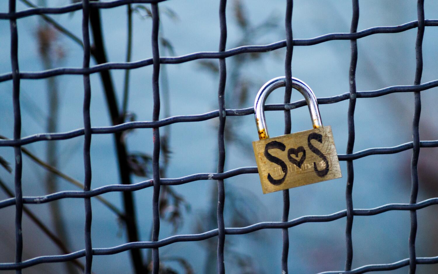 lock on fence with 'sos' reference that also appears as 's loves s' because a heart-shape stands in for 'o'