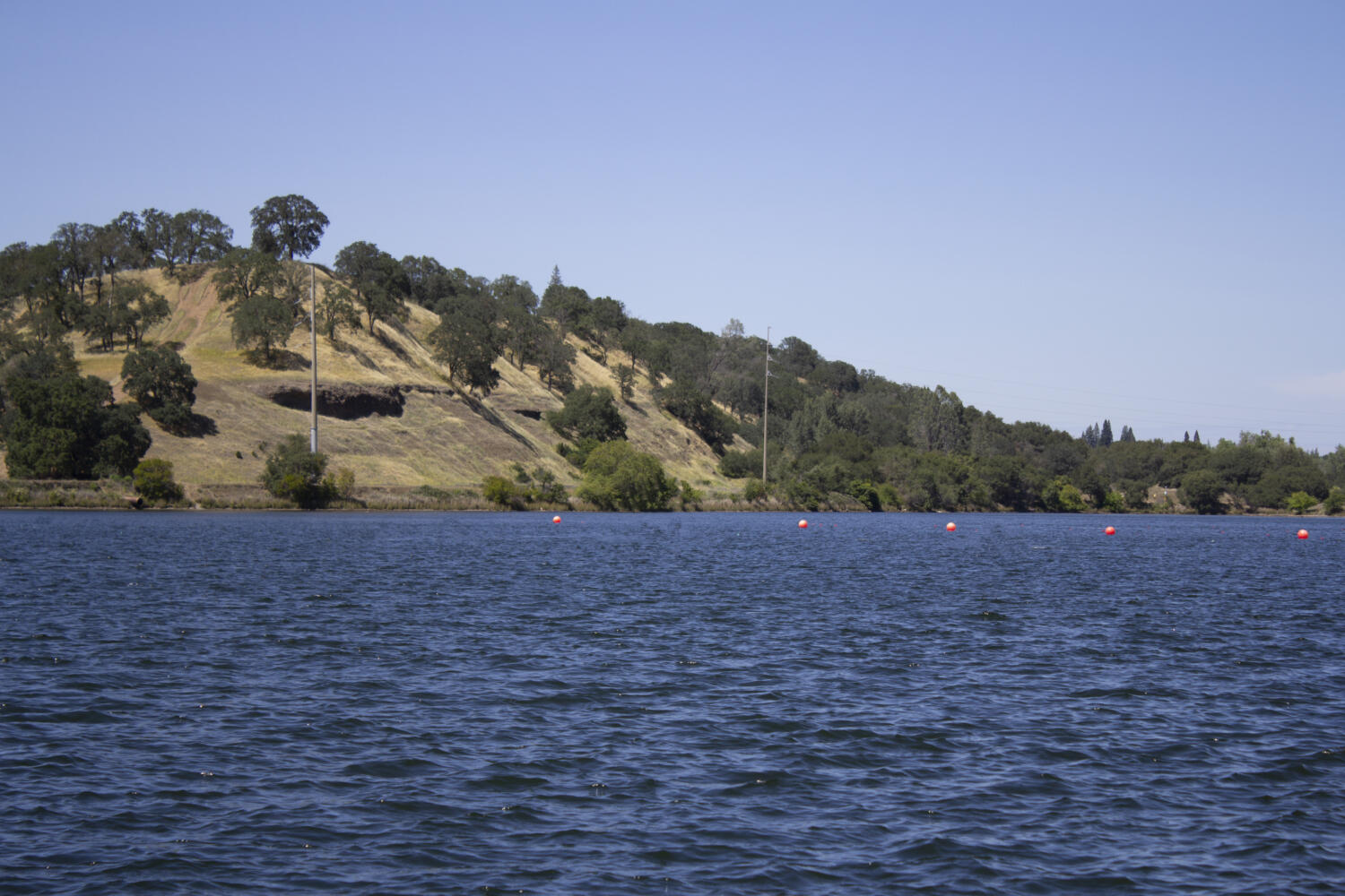 Lake Natoma with a hill in background and the lake's water in focus
