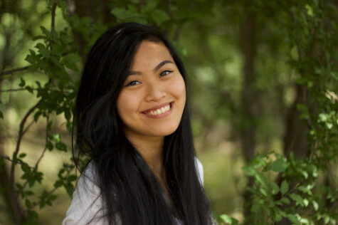 author smiling with long dark and trees in background