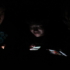 People look down on illuminated phones in a dark room