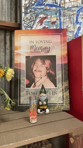 an altar with a photo titled, "in loving memory" with a candle and small gnome