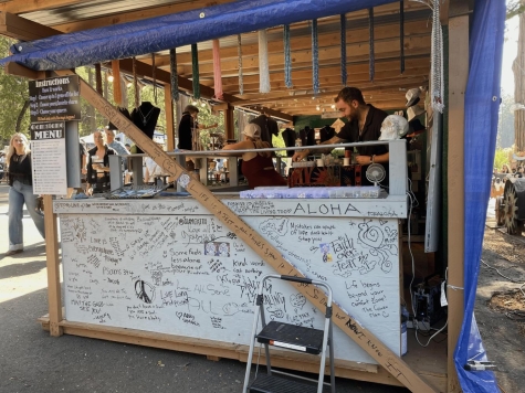 people standing behind a white wooden booth decorated with black writing