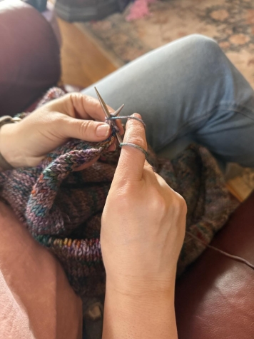 close up of hands kitting a project, resting on the lap of a person in a chair